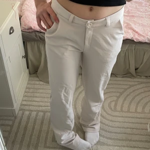 Beiga kostymbyxor från 157 - Säljer ett par stilrena beige byxor från 157 i storlek XS. Byxorna har en rak passform med knapp och dragkedja framtill. Perfekta för en avslappnad look.