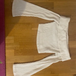 Vit ribbad offshoulder-tröja från shein - Säljer en stilren vit ribbad offshoulder-tröja med långa ärmar. Perfekt för en trendig look. Tröjan har en bred kant upptill som ger en snygg passform. Passar bra till både jeans och kjol. Använts ett par gånger och är en magtröja även. Väldigt snygg och söt, säljer för att har två.