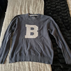 Mörkblå tröja Bondelid - Säljer en mörkblå tröja från Bondelid med en stor vit bokstav 'B' på framsidan. Tröjan har långa ärmar och en rund halsringning. Perfekt för en kallare sommarkväll