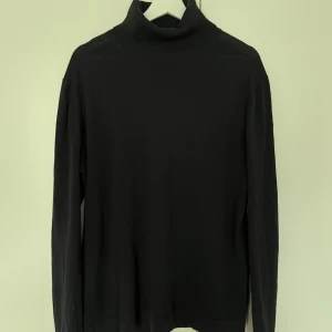 Svart polotröja från Filippa K - Säljer en stilren svart polotröja från Filippa K. Tröjan är tillverkad i 100% bomull och har långa ärmar. Aldrig använd. Nypris 2700kr.