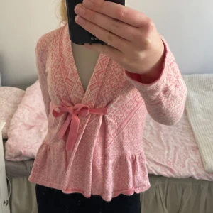 Rosa mönstrad kofta från Odd Molly - Säljer en söt rosa kofta från Odd Molly med ett fint mönster och broderad logga på ryggen. Koftan har långa ärmar, volangdetalj i nederkant och knyts med ett band framtill. Perfekt för en unik och stilfull look!