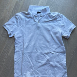 Vit kortärmad pikétröja - Säljer en klassisk vit kortärmad pikétröja med krage och knappar. Perfekt för en stilren och avslappnad look. Passar bra till både jeans och shorts. Bra skick 140 kr +frakt