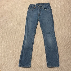Blå jeans från Levi's - Säljer ett par klassiska blå jeans från Levi's med fem fickor och knappgylf. De har en rak passform och är perfekta för en avslappnad stil. Levi's-loggan syns tydligt på baksidan. Perfekta för vardagsbruk!