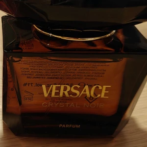 Versace Crystal Noir Parfum - Elegant och mystisk parfym från Versace i en mörk, fyrkantig flaska med gyllene detaljer. Crystal Noir är känd för sin djupa och sensuella doftprofil, perfekt för den som vill ha något unikt och sofistikerat. Ny flaska i 90 ml kolla gärna mina andra annonser jag har ute