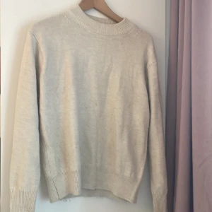 Beige stickad tröja med rund hals - Enkel och stilren beige stickad tröja med rund halsringning och ribbade muddar. Perfekt för lager-på-lager och passar till allt. Långärmad modell i mjukt material som håller dig varm under kyliga dagar.