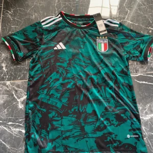 Italien Adidas fotbollströja grön/svart - Snygg Italien fotbollströja från Adidas med unikt grönt och svart grafiskt mönster. Tröjan har broderat landslagsemblem med fyra stjärnor och klassiska Adidas-ränder på axlarna. Tillverkad i lätt och ventilerande polyester.