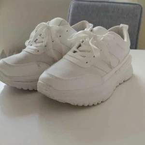 Vita chunky sneakers med snörning - Snygga helvita chunky sneakers med tjock sula och klassisk snörning. Skorna har en sportig vibe och passar perfekt till streetwear. Tillverkade i syntetmaterial och textil för en fräsch look.