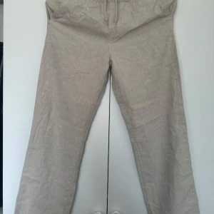Beiga linnebyxor från Kappahl - Snygga och luftiga beiga linnebyxor från Kappahl med dragsko i midjan. Perfekta för varma dagar och chill stil. Raka ben och enkel design som passar till det mesta. Superbekväma och lätta att matcha med t-shirt eller skjorta. Pris går att diskuteras