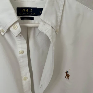 Vit Ralph Lauren Skjorta - Strl S, Slim Fit - Hej säljer nu min fina Ralph Lauren skjorta i storlek S och den sjukt populära modellen Slim Fit. Den är i nyskick och kommer vara otroligt snygg på sommaren. Nypris cirka 1600kr! Vid frågor eller fundering tveka inte på att höra av dig! 🌊🍾