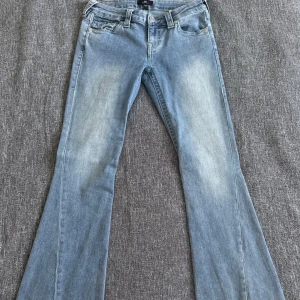 True Religion bootcut jeans - Säljer ett par ljusblå jeans från True Religion med klassisk bootcut och snygga detaljer på bakfickan. 