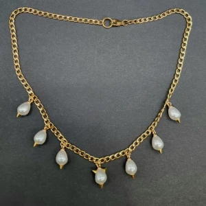 Guldfärgat halsband med pärldroppar - Stilrent halsband med chunky guldfärgad kedja och sju droppformade vita pärlor som hänger längs kedjan. Rostfrit stål, glaspärlor. Längd-40cm,kedjetjocklek-4cm 