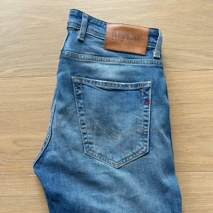 Replay Grover straight jeans blå 29 - Blå jeans från Replay, modell Grover, med straight fit. Klassisk femficksdesign, snygga slitningar och Replay-läderpatch bak i midjan. Jeansen är i denim med en något ljusare tvätt och raka ben. Perfekta för dig som gillar en clean och tidlös look.