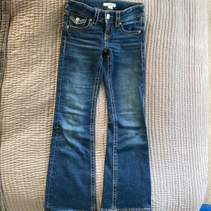 Blå bootcut jeans från Gina Tricot - Snygga blå y2k jeans från Gina Tricot i klassisk bootcut-modell. Jeansen har markerade sömmar, fickor med lock och knapp bak samt normal passform. Perfekta för dig som gillar en clean stockholmstil! 