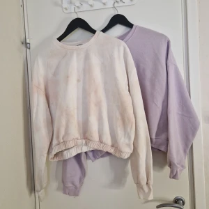 Två sweatshirts - Pastel lila tröja välanvänd sweatshirt i crop top modell. Kan finnas fläckar. Vit/rosa croppad tie dye sweatshirt, använd fåtal gånger, sweatshirt i crop top modell.  Finns fläckar som inte får bort men dom smälter ändå in med mönstret. Båda är storlek L/XL men upplever att dom är mer mot L.