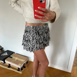 Zebramönstrad kortkjol från KappAhl - Supersnygg kort sommar kjol från KappAhl med svartvitt zebramönster och volang. Kjolen har resår i midjan och är gjord i ett lätt och luftigt material. 💗💗