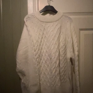 Vit stickad tröja med kabelmönster - Mysig vit stickad tröja med klassiskt kabelstickat mönster framtill. Perfekt till vinter och höst