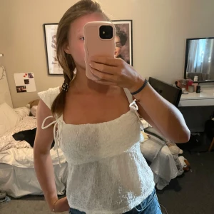 Vit smockad linnetopp från Gina Tricot - Supersöt vit linnetopp från Gina Tricot med rosettknyt band som man kan justera 💗 