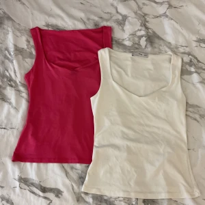 2-pack linne från MNG, vit & rosa - Två stilrena linnen från MNG i storlek XS, ett i klassiskt vitt och ett i fräsch rosa. Båda har v-ringad hals och ärmlös design med figurnära passform. Perfekta att matcha till jeans eller kjol för en enkel och snygg look.