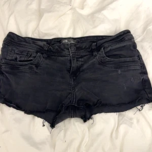 Svarta jeansshorts från LTB - Snygga svarta jeansshorts från LTB med råa, fransiga kanter och klassisk femficksdesign. Shortsen har låg midja och slitna detaljer