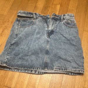 Blå jeanskjol från See See Paris - Säljer en unik blå jeanskjol från See See Paris i storlek S. Kjolen är i kort modell med femficksdesign, bälteshällor och dragkedja framtill. 