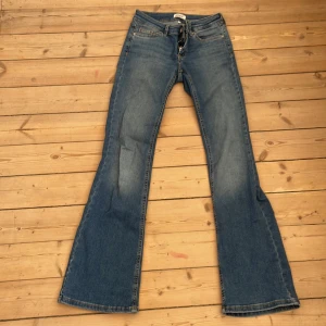 Blå bootcut jeans från ONLY XS - Snygga blå jeans från ONLY i bootcut-modell med låg midja. Klassisk femficksdesign, tillverkade i mjukt bomullsjeans med lite stretch. Perfekta för dig som gillar en retro vibe och vill ha ett par jeans som sitter tajt upptill och släpper vid benen.