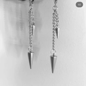 Silvriga örhängen med kedjor och spikes - Säljer ett par coola silvriga örhängen med dubbla kedjor och konformade spikes. De har en edgy vibe och passar perfekt om du gillar statement-smycken. Kedjorna ger extra rörelse och attityd till din look.