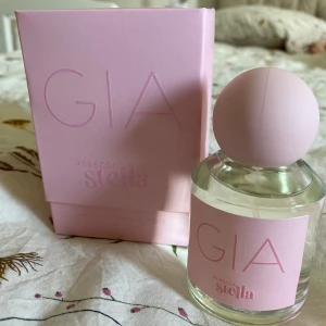Rebecca Stella GIA NY! - Säljer en parfym från Rebecca Stella, GIA, i en stilren glasflaska med rund, matt ljusrosa kork och matchande ljusrosa etikett. Kommer i en snygg rosa box. Flaskan rymmer 50 ml och har en modern, feminin design som känns både trendig och söt.