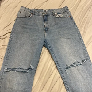 Ljusblå ripped jeans från 157, XL - Ljusblå jeans från 157 i storlek XL med slitna hål över knäna, fransiga benslut. Klassisk femficksmodell i bomullsjeans. Knapt alldir använda