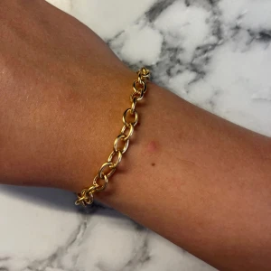 Chunky guldarmband med stora länkar - Snyggt chunky guldplaterat armband  med stora, ovala länkar. Perfekt statement piece som ger en cool vibe till din outfit. Kommer i en söt rosa organzapåse. Passar dig som gillar trendiga accessoarer och vill sticka ut lite extra. 