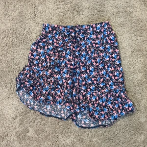 Blommig kjol från Mywear Young - Snygg kjol  från Mywear Young med blommigt mönster i blått, rosa och svart. De har en loose passform och elastisk midja för extra komfort. Perfekta för varma sommardagar💞