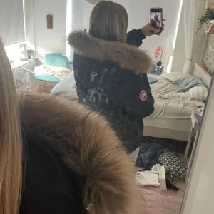 Svart Canada Goose dunjacka med päls - Säljer en svart dunjacka från Canada Goose med stor fluffig päls runt huvan. Har inte andvänt jackan alls mycket så den är väldigt bra skick och är inte sönder någonstans. Jackan är äkta och är köpt på deras hemsida. Nypris: 10000+ 