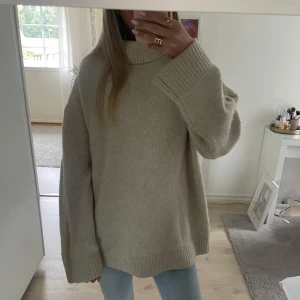 Beige oversized polotröja  - Supermysig beige polotröja i oversized modell med långa ärmar och bred ribbad krage. Perfekt för lager-på-lager och chill höst- och vinterstil. Stickad känsla och loose fit gör den extra comfy till jeans eller leggings.