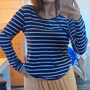 Randig långärmad tröja i marinblått - Snygg långärmad tröja med marinblå och vita horisontella ränder. Tröjan har en rund halsringning och är i ett mjukt, bekvämt material som passar perfekt till jeans eller kjol. Storlek 44 men liten i storlek, skulle säga S/M🥰