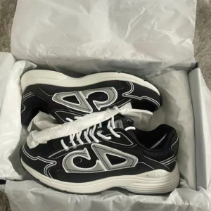 Svarta Dior B30 sneakers med silverdetaljer - Snygga Dior B30 sneakers i svart med silvriga detaljer och vit sula. Skorna har en sportig vibe med mesh och syntetmaterial, samt tydliga loggor på sidan och plösen. Vita snören och rund tå ger en clean look som sticker ut.