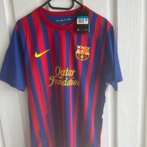 Barcelona David Villa matchtröja Nike - FC Barcelona matchtröja med David Villa och nummer 7 på ryggen. Klassisk design med blå och röda vertikala ränder, officiellt klubbmärke och Nike-logga på bröstet. Tryckta sponsorer i gult och rund hals. Tillverkad i lätt och ventilerande material.