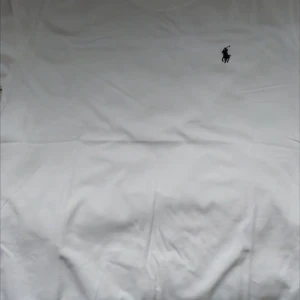 Vit t-shirt från Polo Ralph Lauren - Vit klassisk t-shirt från Polo Ralph Lauren med rund hals och ikonisk broderad logga på bröstet. Tillverkad i mjuk bomull och har en clean, stilren look som passar perfekt till jeans eller shorts.