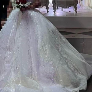 Glittrig vit balklänning med paljetter - Magisk långklänning i vitt med glittriga paljettdetaljer och vackert mönster. Klänningen har en voluminös kjol och markerad midja, perfekt för bal eller fest. Materialet skimrar i ljuset och ger en riktigt lyxig känsla. V-ringad upptill och med eleganta detaljer över hela klänningen  En jättefin brudklänning som endaste använde 3 till 4 timmar prisen kan alltid diskuteras vid snabbaffär köpte den för 20000kr säljer för 7000kr storlek 38 till 44 om man önskar hyra det gàr bra