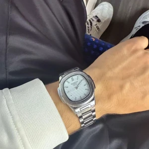 Silverfärgad klocka - Stilren klocka i silverfärgat stål med länkarmband och vit urtavla med diskreta ränder. Klockan har en modern, fyrkantig form och minimalistiska svarta index. Perfekt accessoar för dig som gillar en clean look.