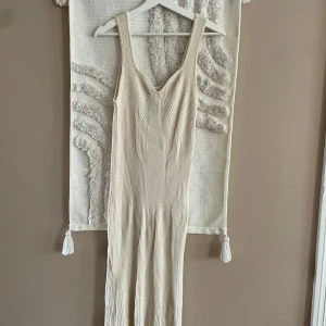 Beige ribbad långklänning Gina Tricot - Supersnygg beige långklänning från Gina Tricot i ribbat material. Klänningen har breda axelband, v-ringning och en figurnära passform som framhäver siluetten. Perfekt för dig som gillar stilrena och trendiga plagg.
