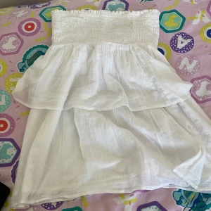 Vit volangklänning från Gina  - OBS : om man har större storlekar så kan man använda denna som en gullig topp!! Superfin vit klänning med dubbla volanger. Lätt och luftig i bomull, perfekt för varma dagar. Klänningen har en söt och flowy känsla som passar till sneakers eller sandaler.