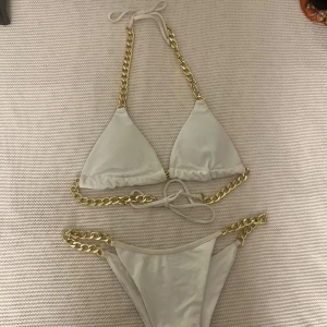 Vit bikini med guldkedjor - Supersnygg vit bikini med guldkedjor i storlek M💗Jag köpte second hand och finns inga lappar så vet ej vart den kommer ifrån🫶