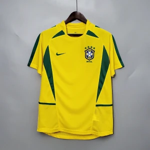 02 BRASILIEN (RETRO)  - Gul Brasilien fotbollströja från Nike med gröna detaljer längs sidor och axlar. Broderat CBF-emblem och Nike-logga på bröstet. Tillverkad i lätt och ventilerande polyester, perfekt för match eller träning. Klassisk rund hals och korta ärmar. Leverans 5-20 dagar. 