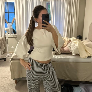 Vit topp med vida ärmar - Säljer en stilren vit topp med vida, trekvartsärmar och croppad passform. Toppens material känns mjukt och har en lätt stretch. Perfekt för dig som gillar minimalistisk stil med en twist. Passar snyggt till både jeans och kjol.