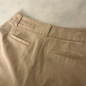 Beiga kostymbyxor från Fashion Nova - Snygga beiga kostymbyxor från Fashion Nova i klassisk modell med raka ben och hällor för bälte. Skriv för fler frågor om mått eller annat💗