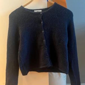 Mörkblå kofta från Gina Tricot - Mysig mörkblå kofta från Gina Tricot i fluffig stickad ullmix. Klassisk rund halsringning och knäppning med svarta knappar framtill. Perfekt för lager-på-lager och passar till både jeans och kjol. Använts en gång och är som ny!   ❗️ARTIKELN ÄR RESERVAD!!!!!!❗️KÖP INTE!!