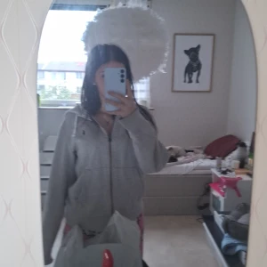 Grå hoodie med dragkedja - Mysig grå hoodie med dragkedja och huva. Jackan har en enkel design med fickor framtill och ribbade muddar. Perfekt för chill dagar eller när du vill ha något bekvämt och stilrent.