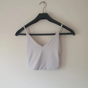 Vit croppad linnetopp från Amisu - Säljer en stilren vit croppad linnetopp från Amisu. Toppen har smala justerbara axelband och v-ringning både fram och bak. Perfekt för dig som gillar minimalistisk stil och vill ha något enkelt men snyggt till sommaren. Helt skick dock lite mörkare i färgen