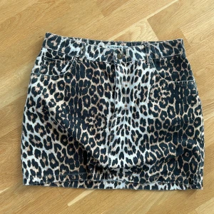 Leopardmönstrad jeanskjol Pull&Bear - Snygg kort jeanskjol från Pull&Bear med leopardmönster. Kjolen har klassisk femficksdesign, bälteshällor och knappstängning framtill. Perfekt statement-plagg för dig som vill sticka ut.