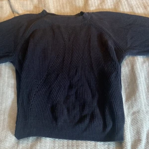Mörkblå stickad tröja Carin Wester - Mörkblå stickad tröja från Carin Wester i storlek M. Tröjan har ett snyggt ribbat mönster och lång ärm. Perfekt för dig som gillar en enkel men stilren look med lite struktur i materialet.