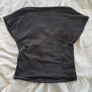 Svart croppad topp med öppen rygg - Svart croppad topp i mjuk bomull med korta ärmar och en snyggt öppen rygg. Enkel och stilren design som passar perfekt till jeans eller kjol. Toppen har en loose passform och är riktigt bekväm att bära.